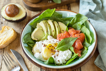 Ketogenic, keto or paleo diet. Delicious breakfast or lunch bowl with salted salmon fish, avocado, boiled egg and spinach on a rustic table.
