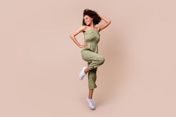 Fototapeta na wymiar Full body photo of stunning young woman curly hair jump defile look empty space wear trendy khaki outfit isolated on beige color background
