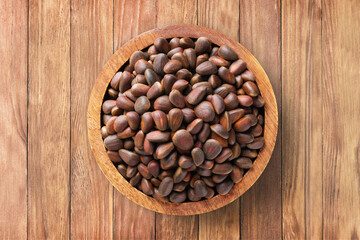 shelled pine nuts in bowl on wooden table background, top view. organic vegetarian food.