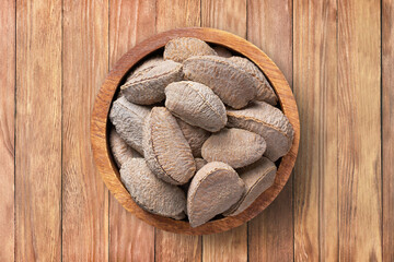 shelled bertholletia, brazil nuts  in bowl on wooden table background, top view. organic vegetarian food.