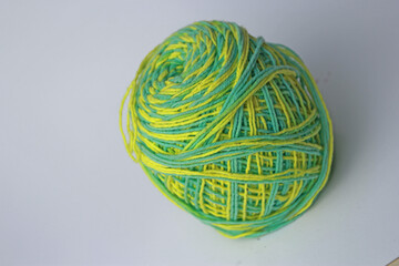 a skein of green wool with a mixture of yellow on a white background.