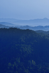 Forest covered hazy layers of hills in a beautiful moody landscape. Environment, seasons, religion and climate concepts