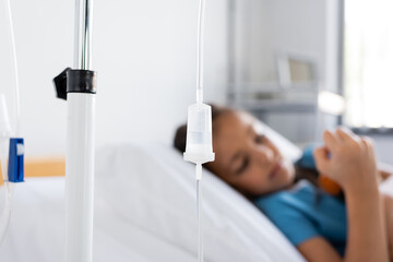 Intravenous therapy on stand near blurred sick child in hospital.