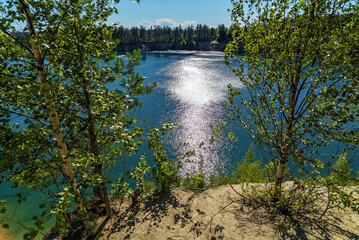 Sun glare on the water . The steep shore of the reservoir.