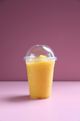 Mango smoothie milk shake with take out glass isolated on pink background