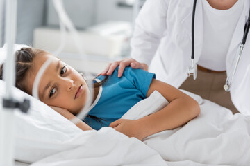 Obraz na płótnie Canvas Pediatrician calming upset girl on hospital bed.