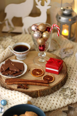 Various Christmas decorations, cup of tea or coffee, sweets, small presents, knitted blanket and candles. Selective focus.