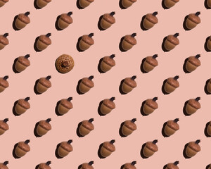 Seamless pattern of identical acorns on a beige background. Instead of one acorn, there was a hat. Autumn print for wallpaper, background. Design for wrapping paper, fabrics, covers and postcards.