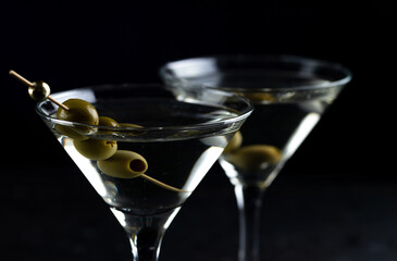 A martini in a triangular glass with olives is on the table