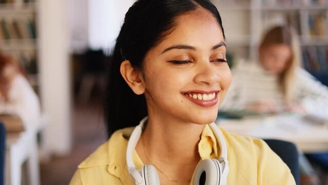 Portrait of smiling inspired indian girl at the university with students on the background. Successful young student in the library. Motivated students.