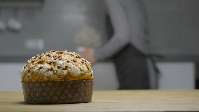 Traditional Italian homemade Christmas panettone typical Milanese with almonds, chocolate chips and sugar, with a woman moving in the background