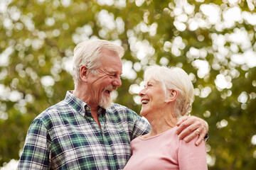 Loving Retired Senior Couple Hugging Outdoors In Countryside Or Garden Together