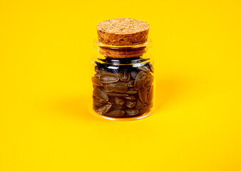 black sunflower seeds in glass jar wine glass. in bucket sunflower seeds on orange yellow background. front view sunflower seeds,