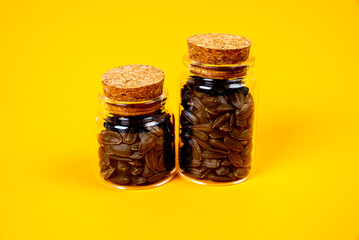 black sunflower seeds in glass jar wine glass. in bucket sunflower seeds on orange yellow background. front view sunflower seeds,