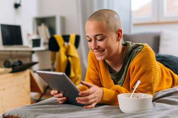 teenager female shaved head use digital tablet in dormitory room
