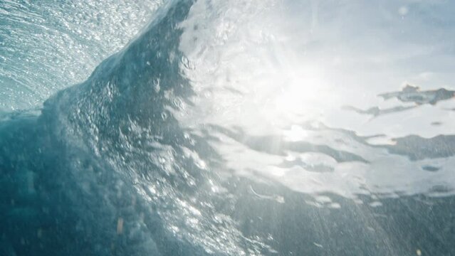 Underwater view of the ocean wave breaking on the shore in the Maldives at sunset