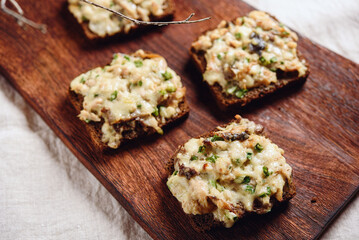 Rye bread toast with smoked mackerel, cream, cheese and green onion on wooden cutting board. Delicious appetizer, tapas. Selective focus - 544612159