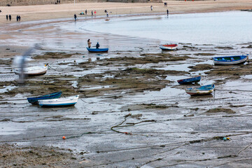 Boats stranded on the beach and people walking