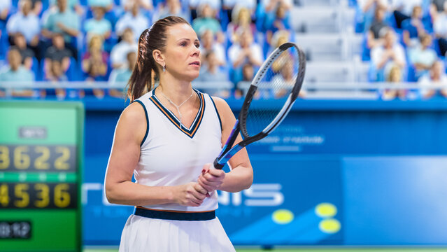 Female Tennis Player Hitting Ball With A Racquet During Championship Match. Professional Woman Athlete Striking Ball. World Sports Tournament With Audience. Side View Photo With People Cheering.