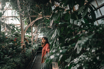 young caucasian woman in red jacket walking calmly relaxed inside lonely quiet botanic garden caressing plants, botanic garden christchurch, new zealand - obrazy, fototapety, plakaty