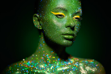 Fashion model woman skin face in bright sparkles, colorful neon lights, beautiful girl sexy lips. Trendy glowing green skin make-up. Art design make up. Glitter metallic shine silver green makeup