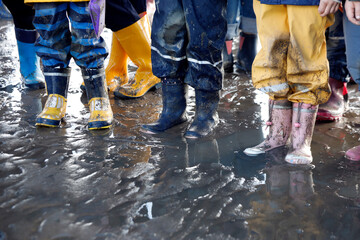 Children's feet in rubber boots, mudflat hike at low tide on the North Sea, close up. - obrazy, fototapety, plakaty
