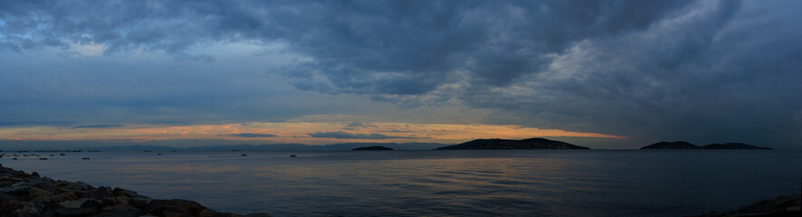 Orange sunset sky and sun over the sea. Water surface and outlines on the horizon.