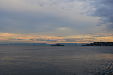 Orange sunset sky and sun over the sea. Water surface and outlines on the horizon.
