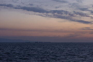 Obraz premium Orange sunset sky and sun over the sea. Water surface and outlines on the horizon.