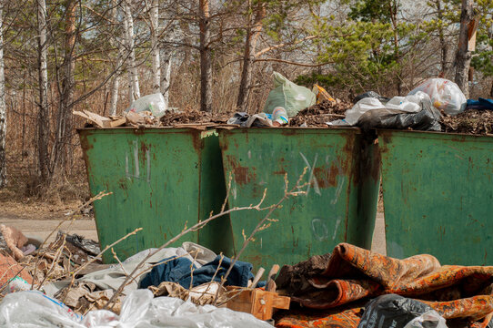 Large, old, rusty metal trash cans. Street trash cans, against the backdrop of a green forest and trees.
