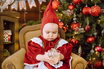 Fototapeta na wymiar cute baby girl sits near the Christmas tree