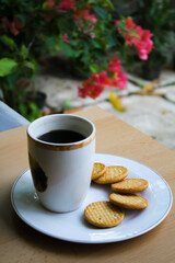 Biscuits and a cup of black coffee on a white plate.