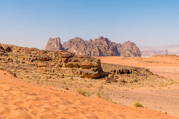 Fototapeta na wymiar A view from a sand dune towards rocky outcrops in the desert landscape in Wadi Rum, Jordan in summertime