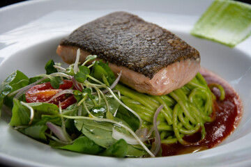 salmon grillado con pastas verdes servido en restaurant elegante
