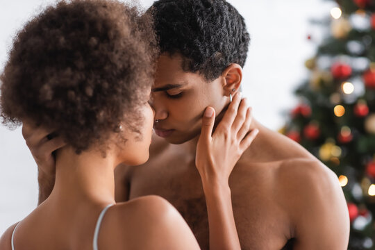 young and sexy african american couple touching each other while standing face to face at home