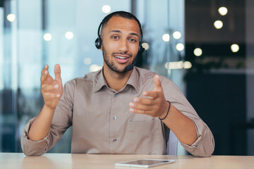 Webcam view, happy african american man talking online video call looking at camera using headset,...