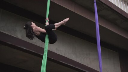 Couple of girls doing aerial yoga under the bridge in a park in Valencia
