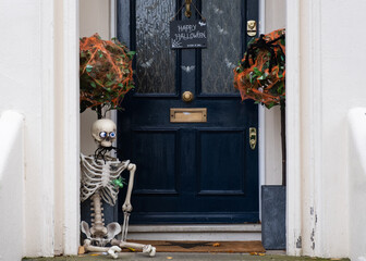Halloween decorations of traditional english house. Skeleton and spider web on the doorstep.