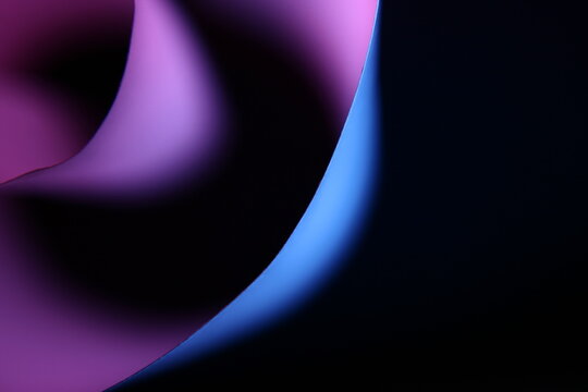 Espiral de papel para impresora de oficina con curvas concèntricas difuminado con luz lateral de color azul y rosa, presentan un hermoso diseño abstracto en bokeh con fondo negro