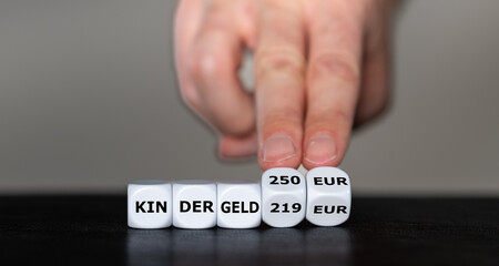 Symbolbild zur Erhöhung des Kindergeldes in Deutschland. Hand dreht Würfel und ändert den...