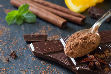 Cocoa powder on spoon on background of chocolate and additives