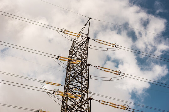 High Voltage Electric Tower on bright silver lining thick soft blue clouds  - Power line tower High voltage Power poles for energy transmission in Lambe - Ogun state, NIGERIA. 