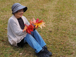 紅葉したカエデを持つ高齢日本人女性