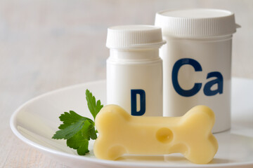 Bone shaped cheese and dietary supplements with calcium and vitamin D on plate, strong and healthy...