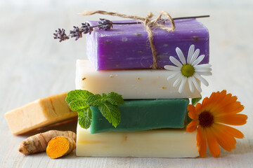 Stack of natural soaps with medicinal plants, flowers and turmeric