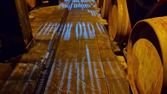 Beautiful illuminations of a corridor with stacked barrels on either side in a wine cellar of a winery in Metsovo in Greece

