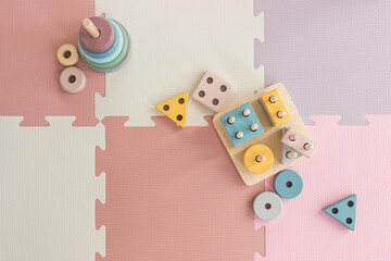 colorful wooden stacking toys on pink play mat in nursery room   - 544641932
