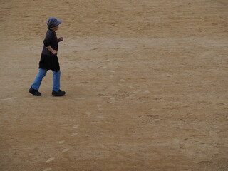 グランドで走る高齢日本人女性	