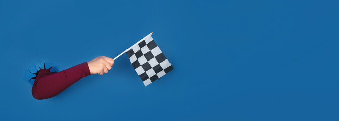 hand holding checkered flag over blue background, panoramic layout
