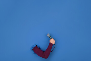 microphone in hand over blue background, layout image